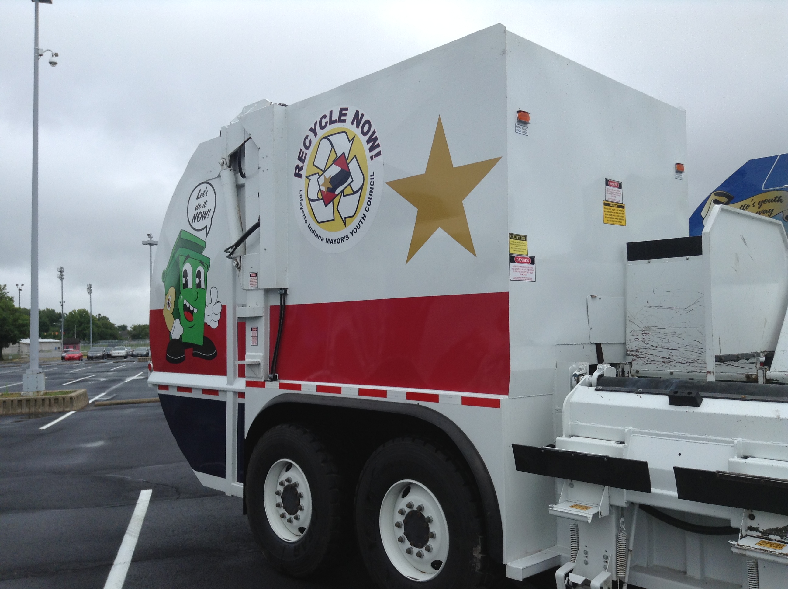 A trash truck with a gold star on the side